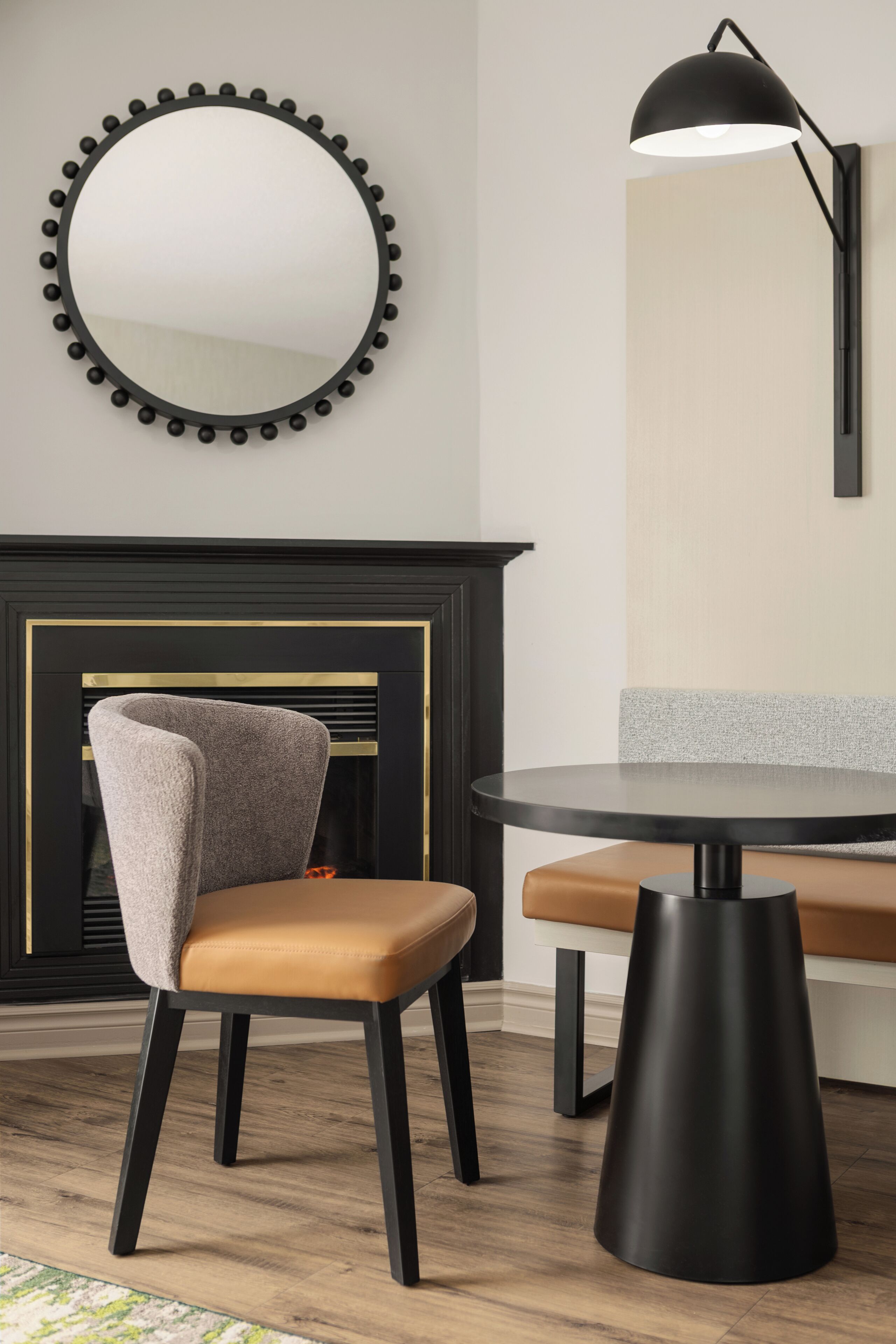 A modern room with a round table, a chair, a lamp, and a fireplace.