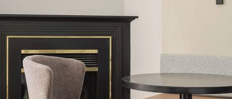 Una habitación moderna con una mesa redonda, una silla, una lámpara y una chimenea.