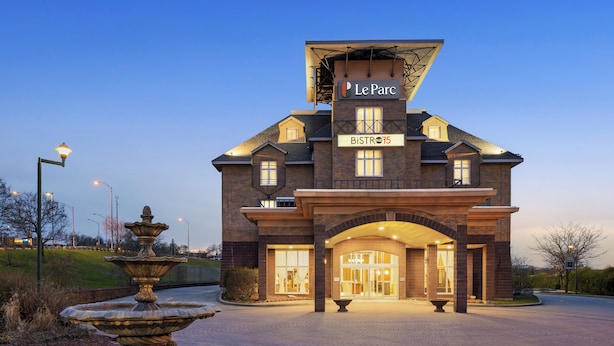 A hotel with a sign reading 'Le Parc Bistro 15,' featuring a brick facade, large windows, and a fountain in the foreground. - Le Parc Gatineau, Tapestry Collection by Hilton (Gatineau)
