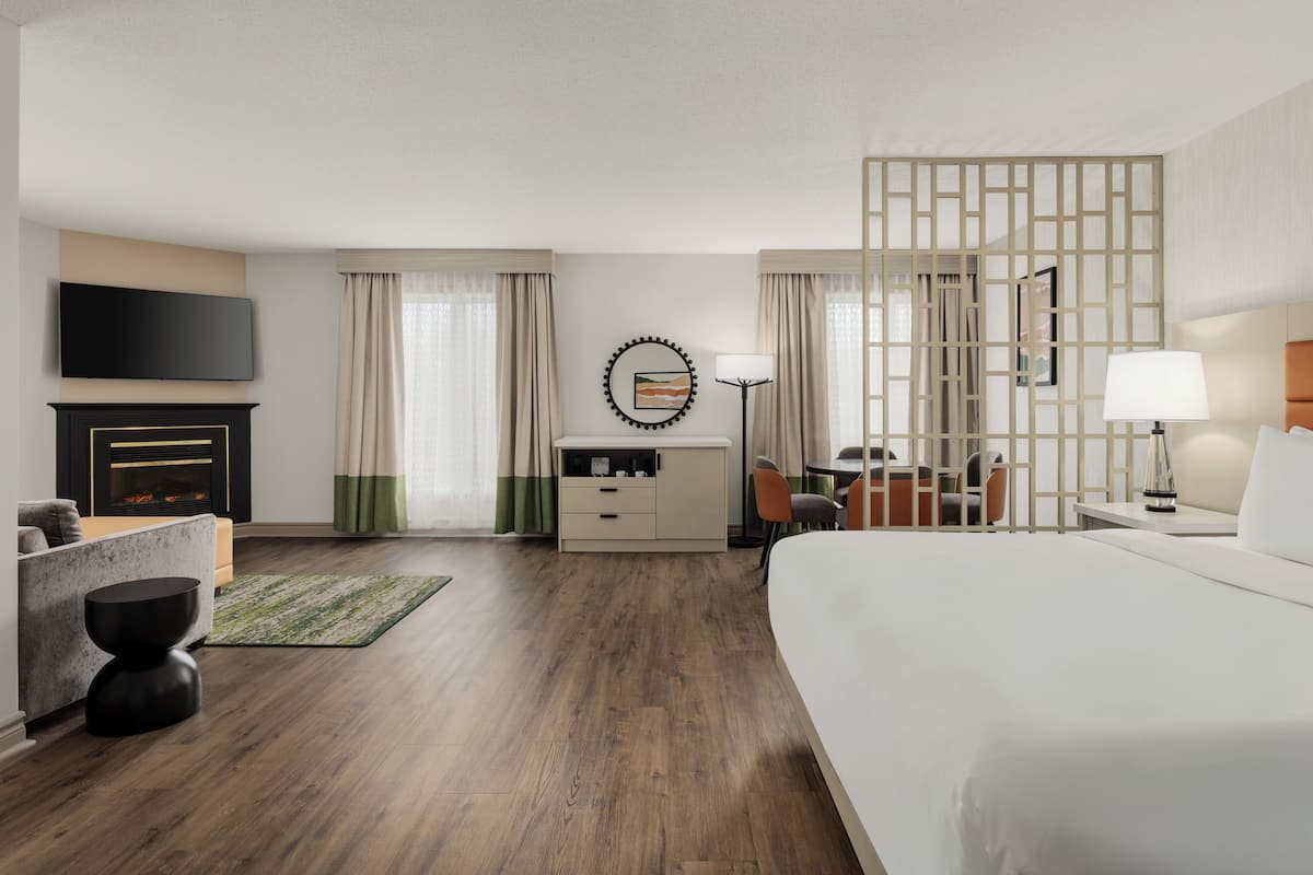 Une chambre d’hôtel comprenant un lit, un bureau, une chaise, une télévision, une cheminée et un panneau décoratif mural.
