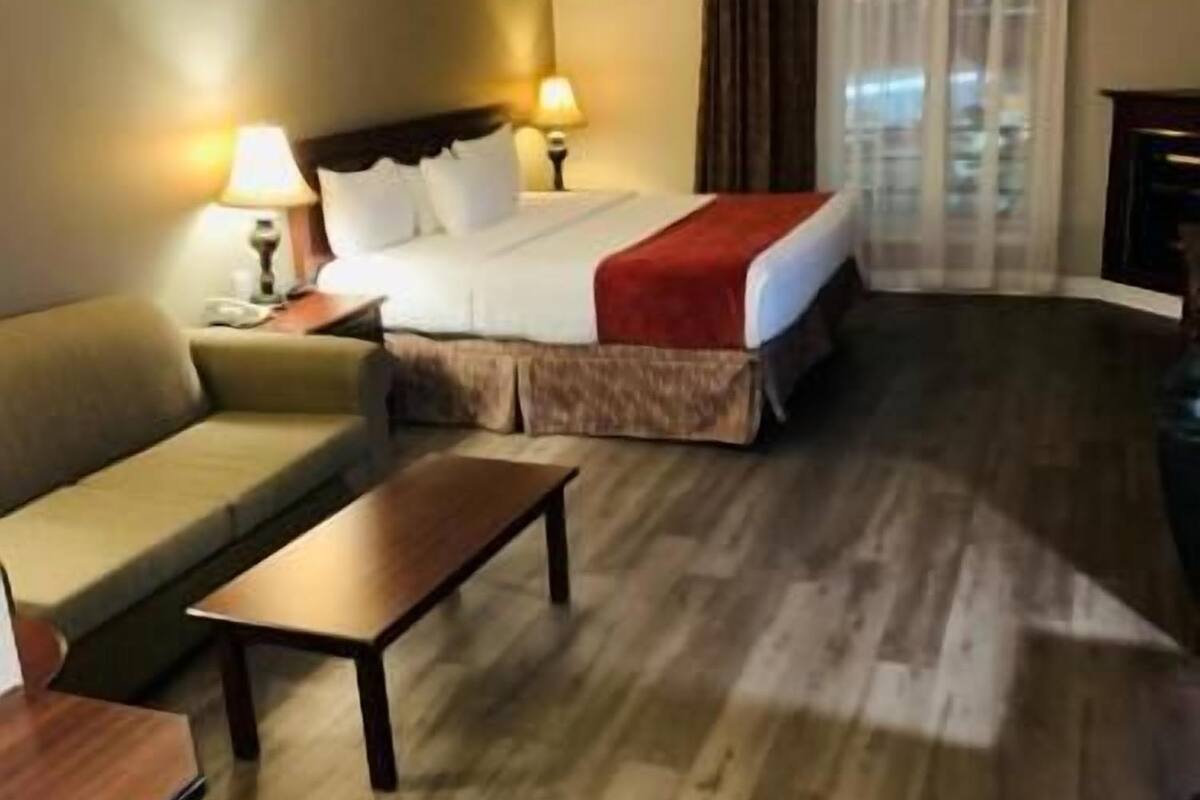 Une chambre d’hôtel avec un lit, un canapé, une petite table et un bureau.