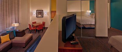 A hotel room with a sofa, a TV, a desk, and a bed.