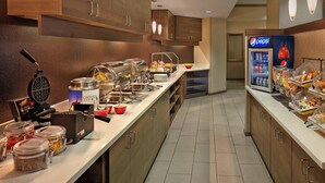 A modern hotel kitchen with a buffet setup, including a waffle maker, jars of condiments, and a Pepsi refrigerator. - Residence Inn by Marriott Hartford Downtown (Hartford)