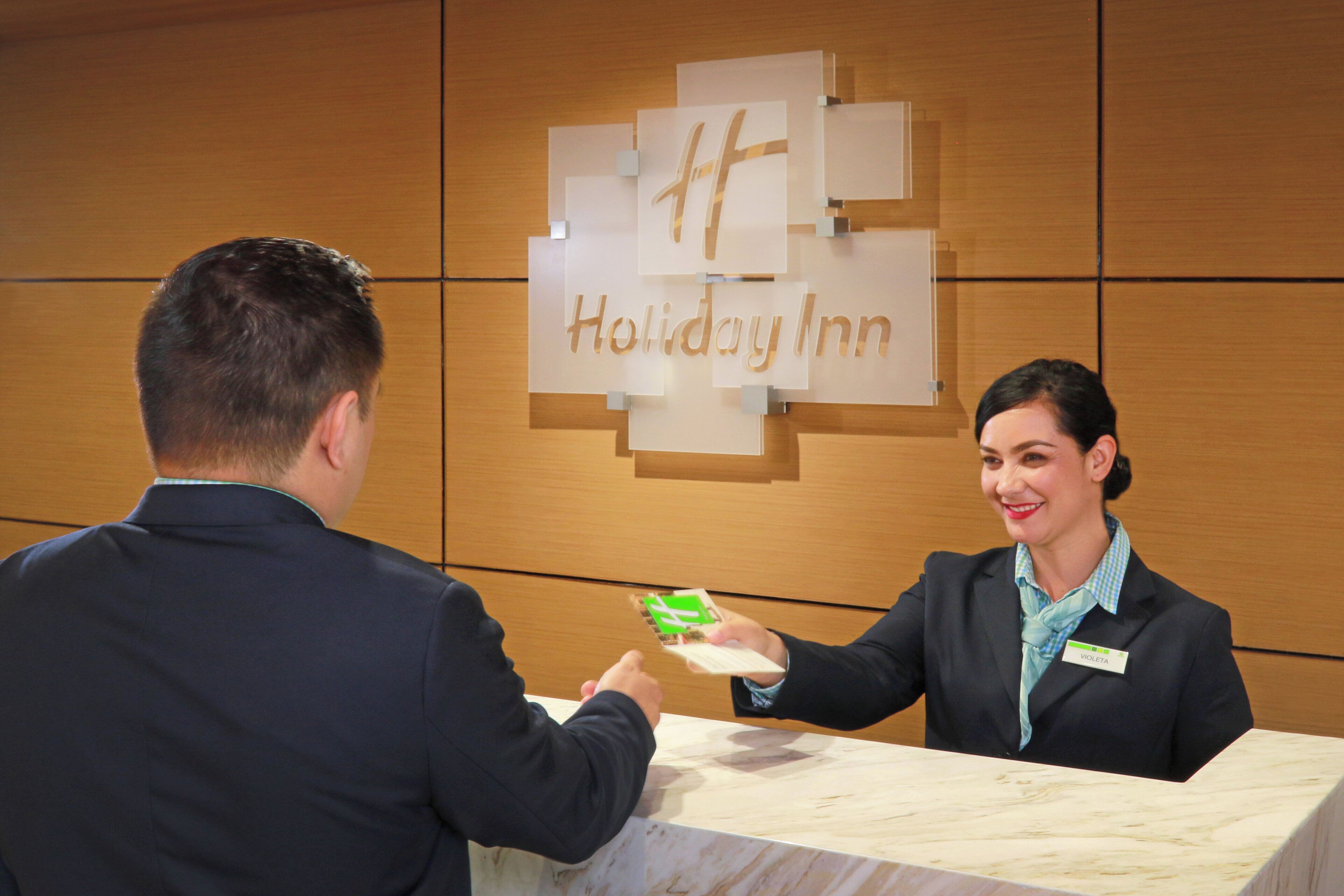 A hotel reception desk with a Holiday Inn sign above.