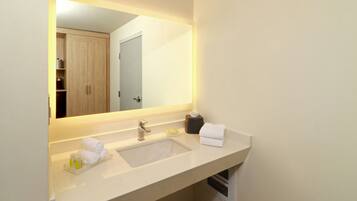 A hotel bathroom with a large mirror, two sinks, and a towel rack.