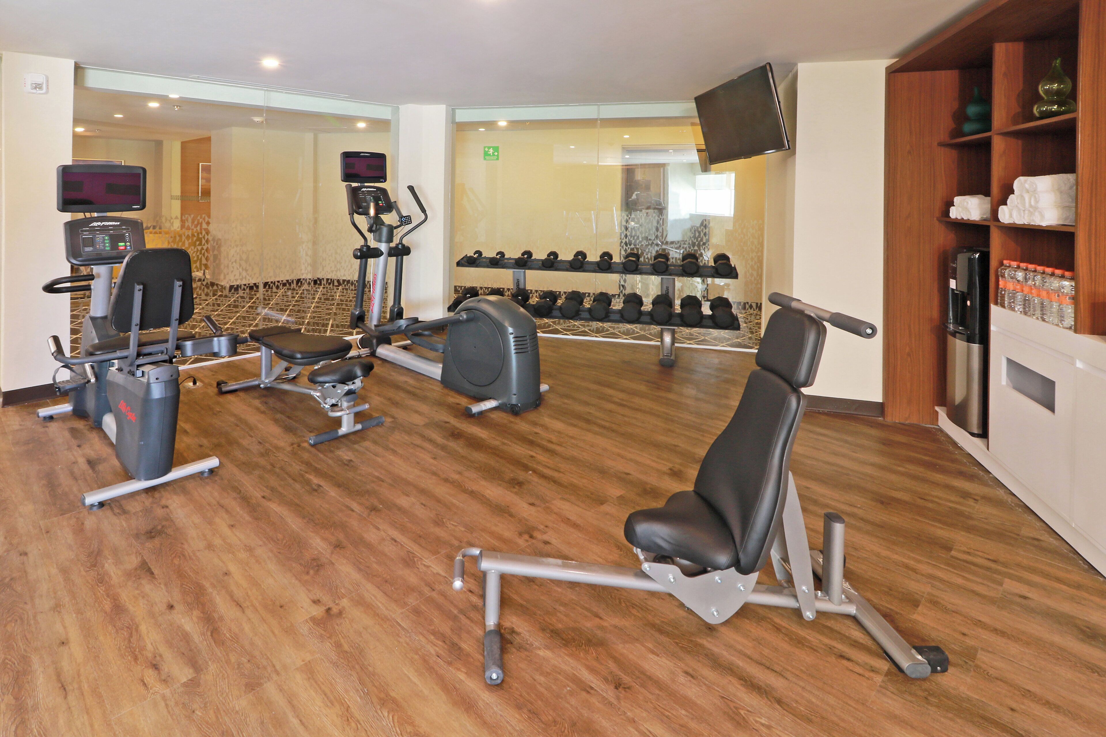Une salle de sport équipée de divers appareils d’exercice, notamment des tapis de course, des appareils de musculation et des haltères.