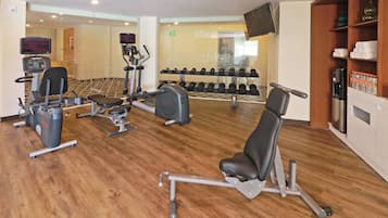 Une salle de sport équipée de divers appareils d’exercice, notamment des tapis de course, des appareils de musculation et des haltères.
