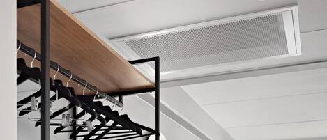 Una habitación de hotel moderna con una cama litera, un escritorio con silla, un televisor y un amplio ventanal con cortinas.