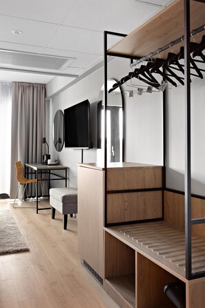 A modern room with a bunk bed, a desk with a chair, a television, and a large mirror.