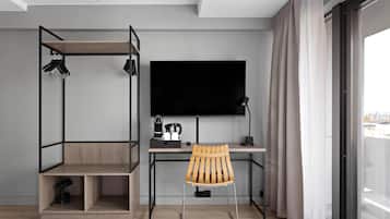 Ein modernes Zimmer mit Schreibtisch, Stuhl und einem großen Fernseher.