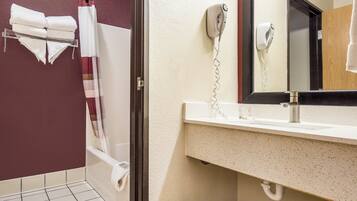 Un baño con ducha, lavamanos y espejo.