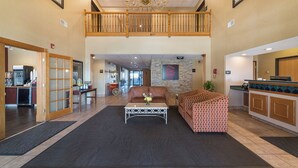 A spacious lobby with a high ceiling, a chandelier, a seating area with patterned sofas, and a vending machine. - Red Roof Inn St Louis - Troy, IL (Troy)