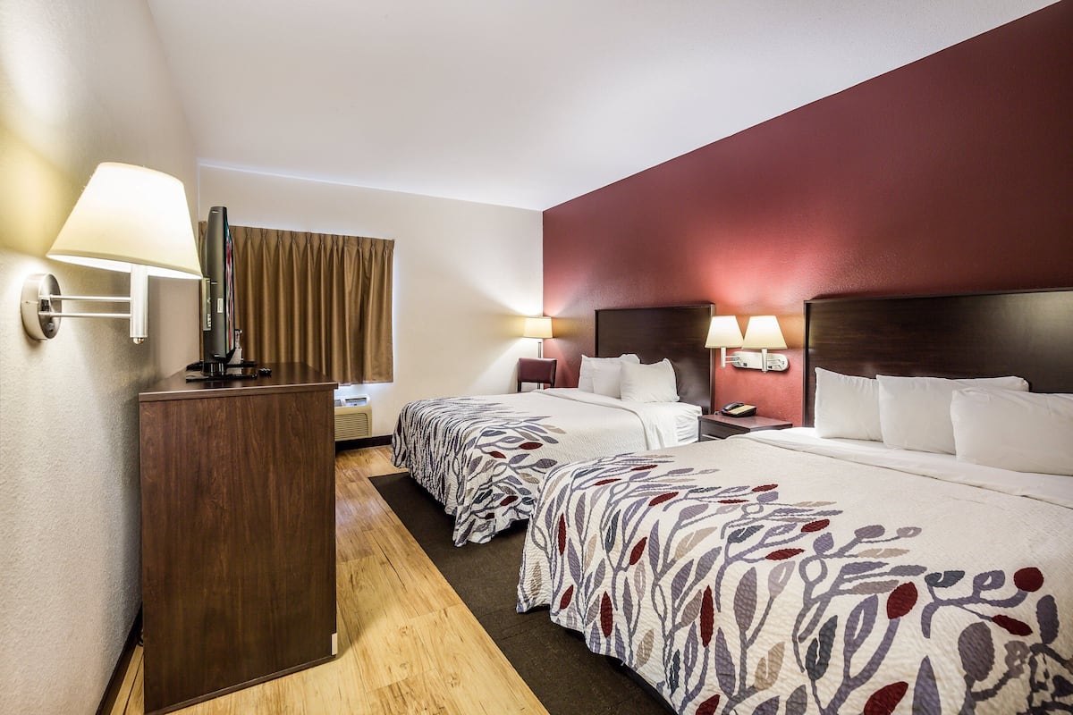 A hotel room with two beds, a desk, and a wardrobe.