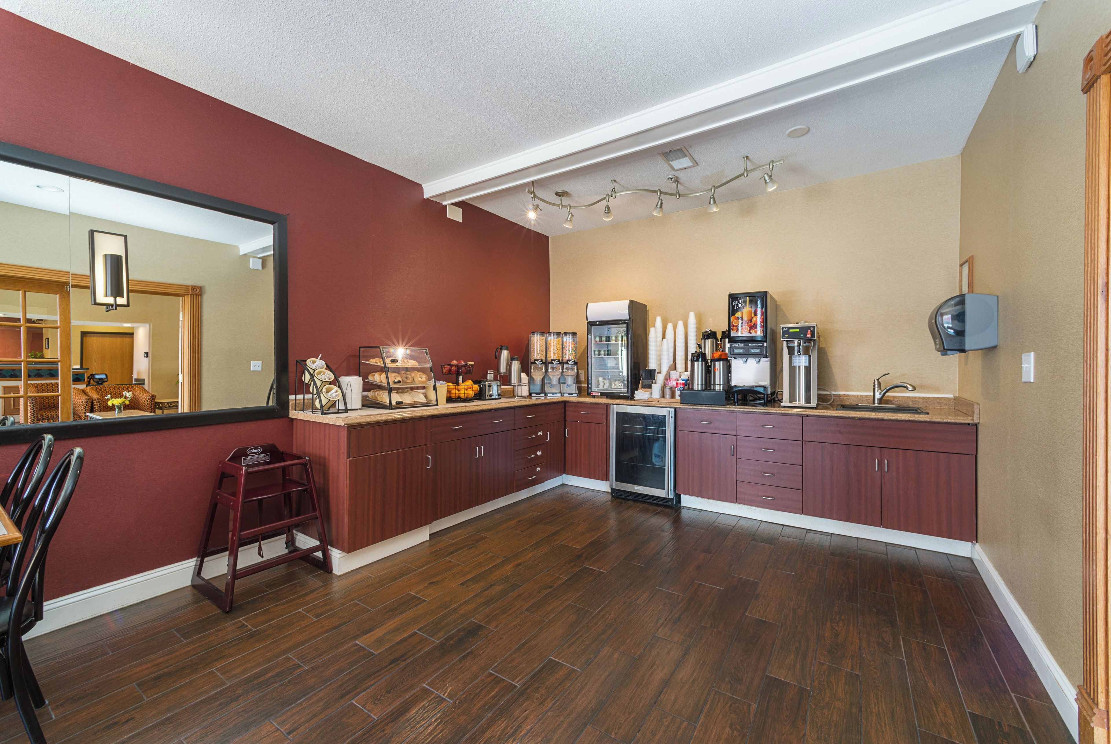 A modern kitchen with wooden cabinets, a built-in dishwasher, and a large island with a coffee station.