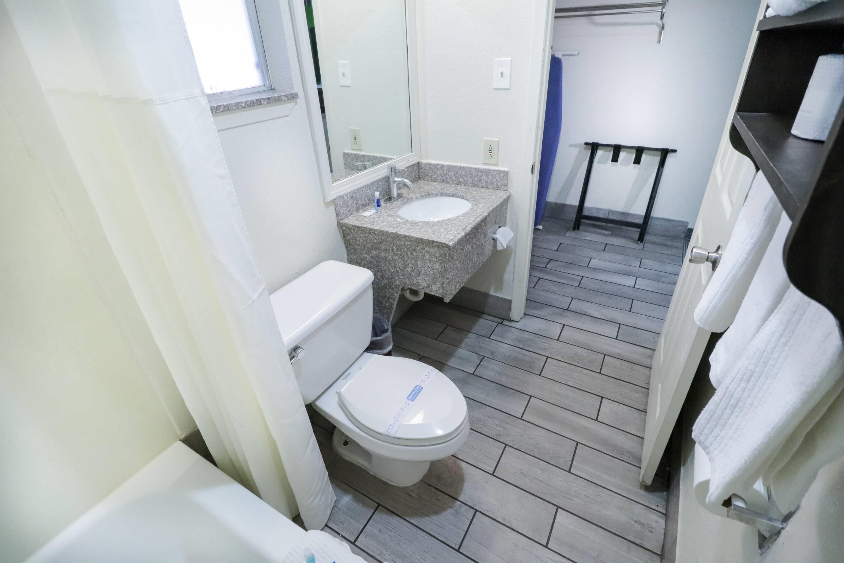 A bathroom with a toilet, sink, and mirror.