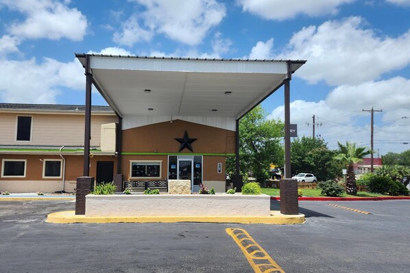 A building with a covered entrance, a star logo, and a parking lot.