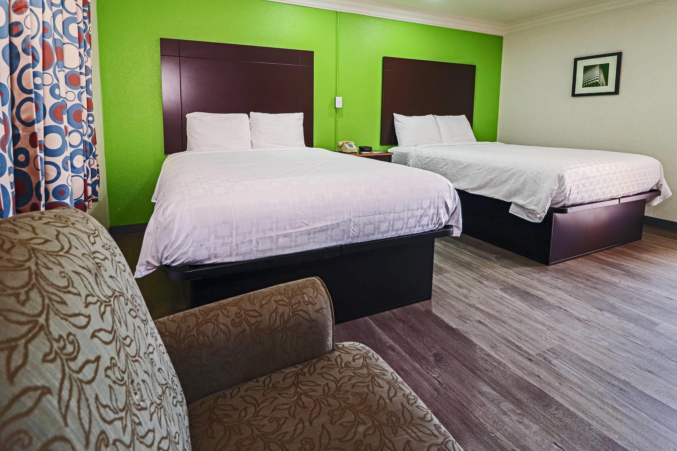 Una habitación de hotel con dos camas, un sofá y una silla estampada.