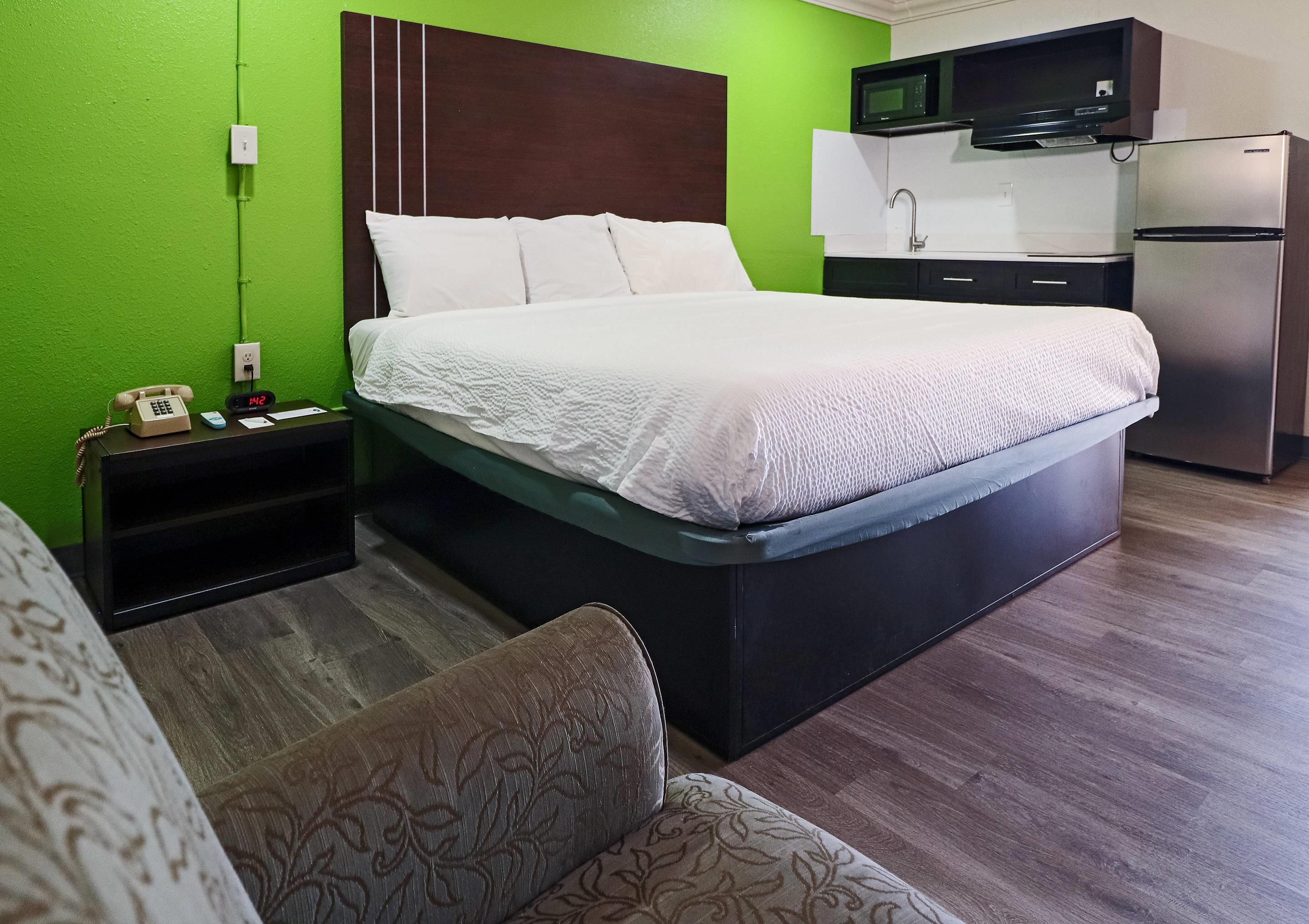 Quarto de hotel com uma cama, mesa de cabeceira com telefone, micro-ondas e frigorífico.