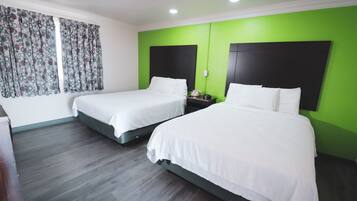 Una habitación de hotel con dos camas, una pared de acento verde y una cortina estampada.