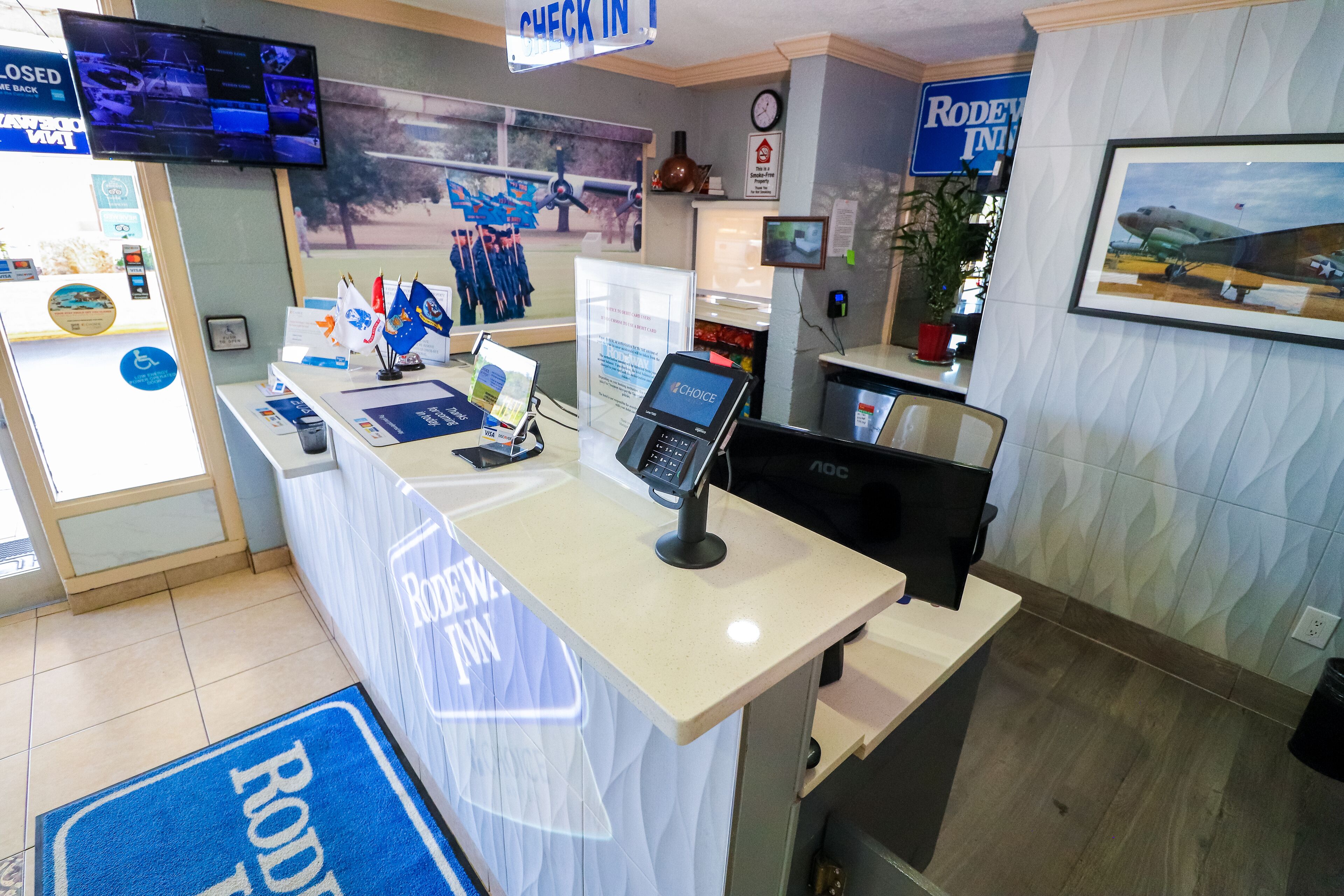 A reception desk with a 'RODEO FUN' sign, a television, and a framed picture of an airplane.