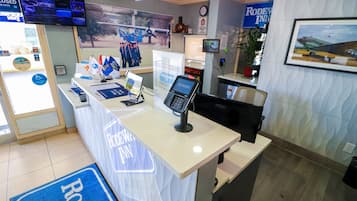 A reception desk with a 'RODEO FUN' sign, a television, and a framed picture of an airplane.