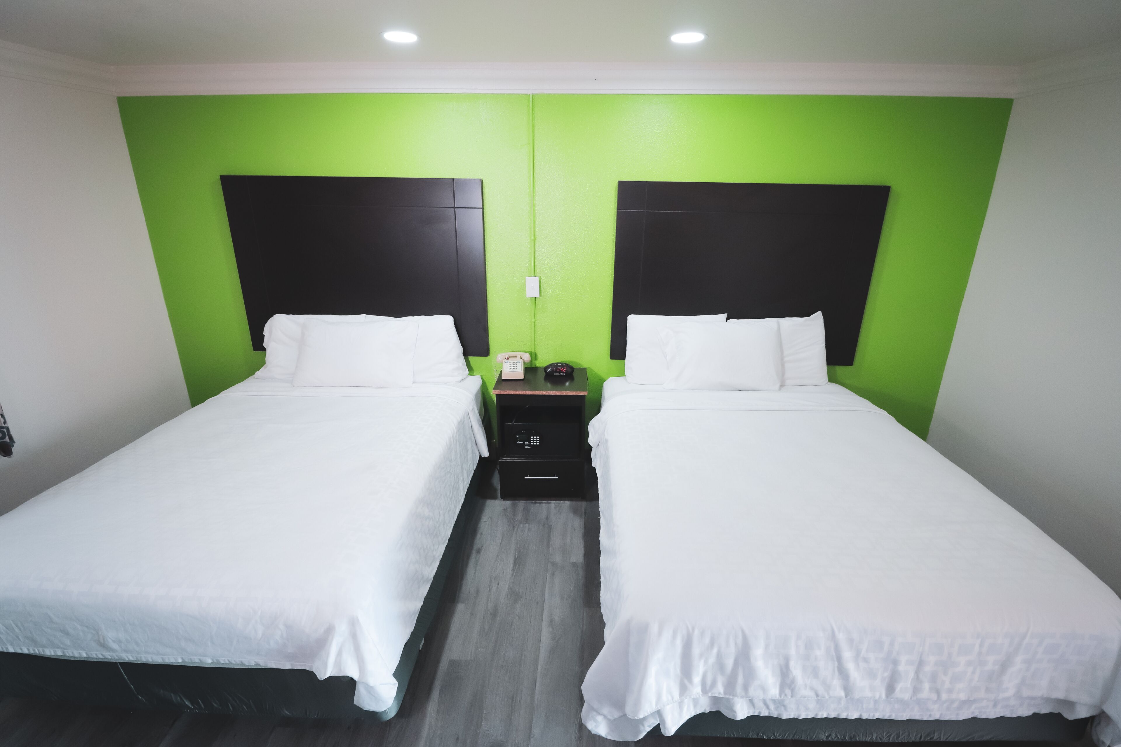 Habitación doble con dos camas, paredes verdes y cabeceros negros.