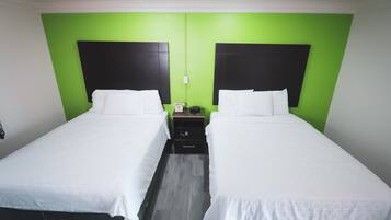 Habitación doble con dos camas, paredes verdes y cabeceros negros.