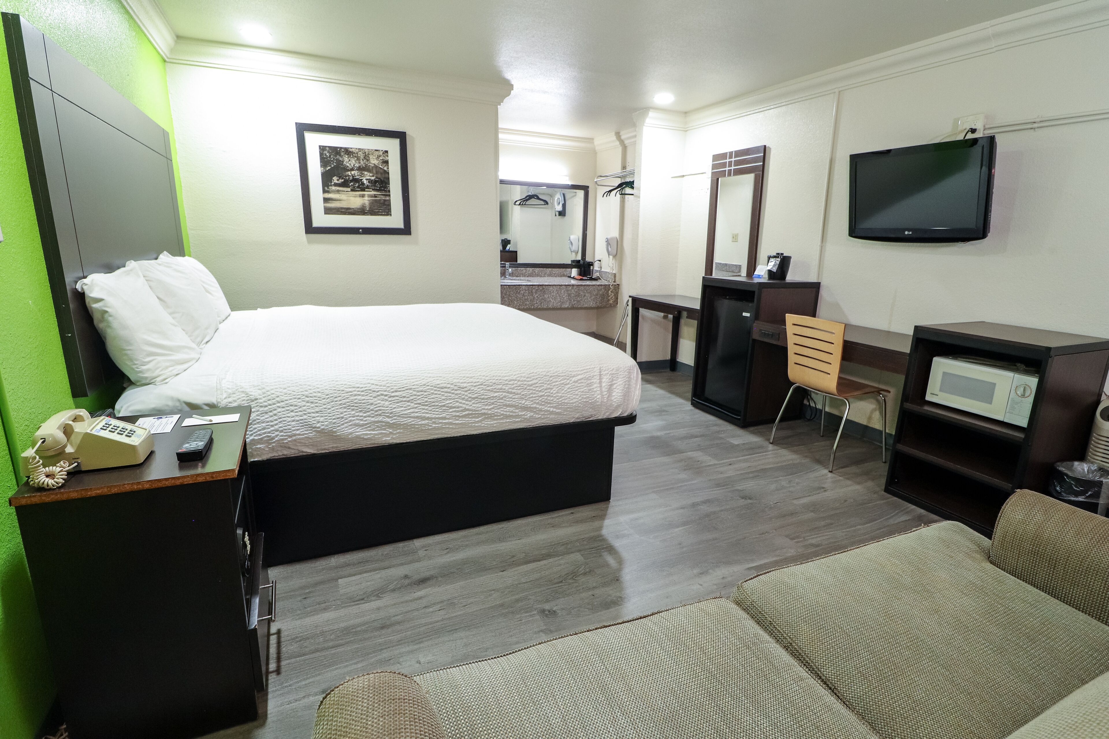 Habitación de hotel con cama, escritorio, televisión, microondas y una silla.