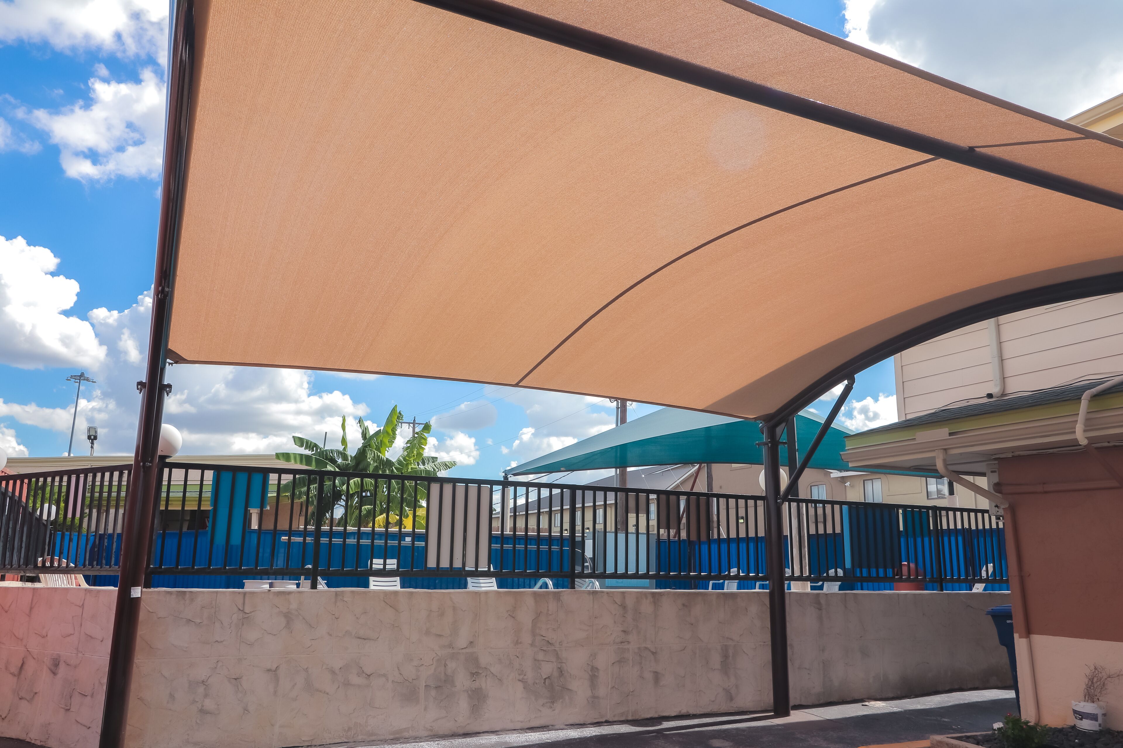A covered outdoor seating area with a concrete wall and metal railing.