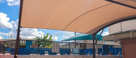 A covered outdoor seating area with a concrete wall and metal railing.