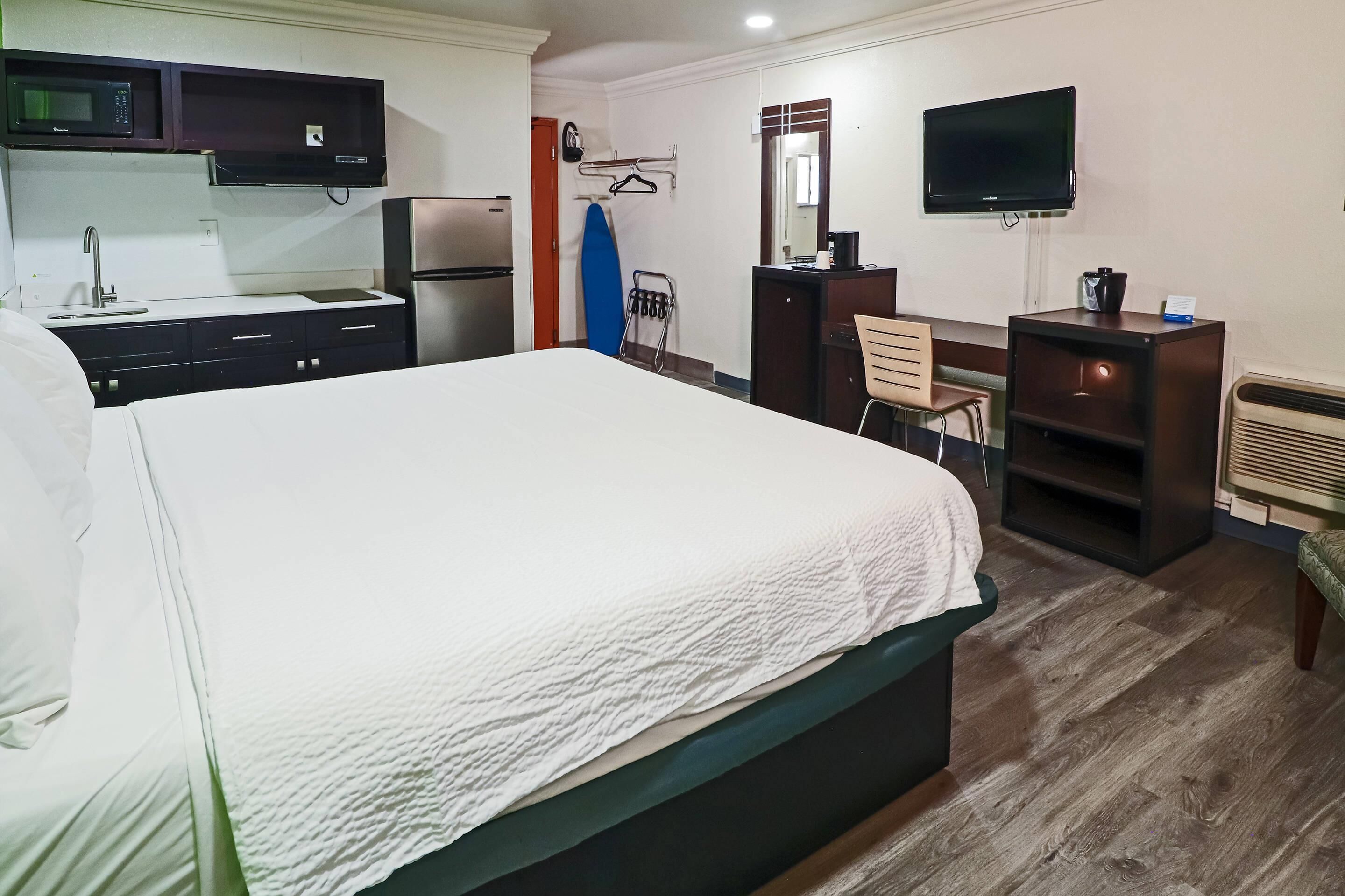 Habitación de hotel con cama, escritorio, televisión, microondas y refrigerador.