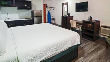 Habitación de hotel con cama, escritorio, televisión, microondas y refrigerador.