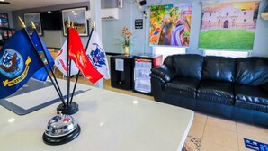 A reception area with flags, a black leather couch, and artwork on the walls.