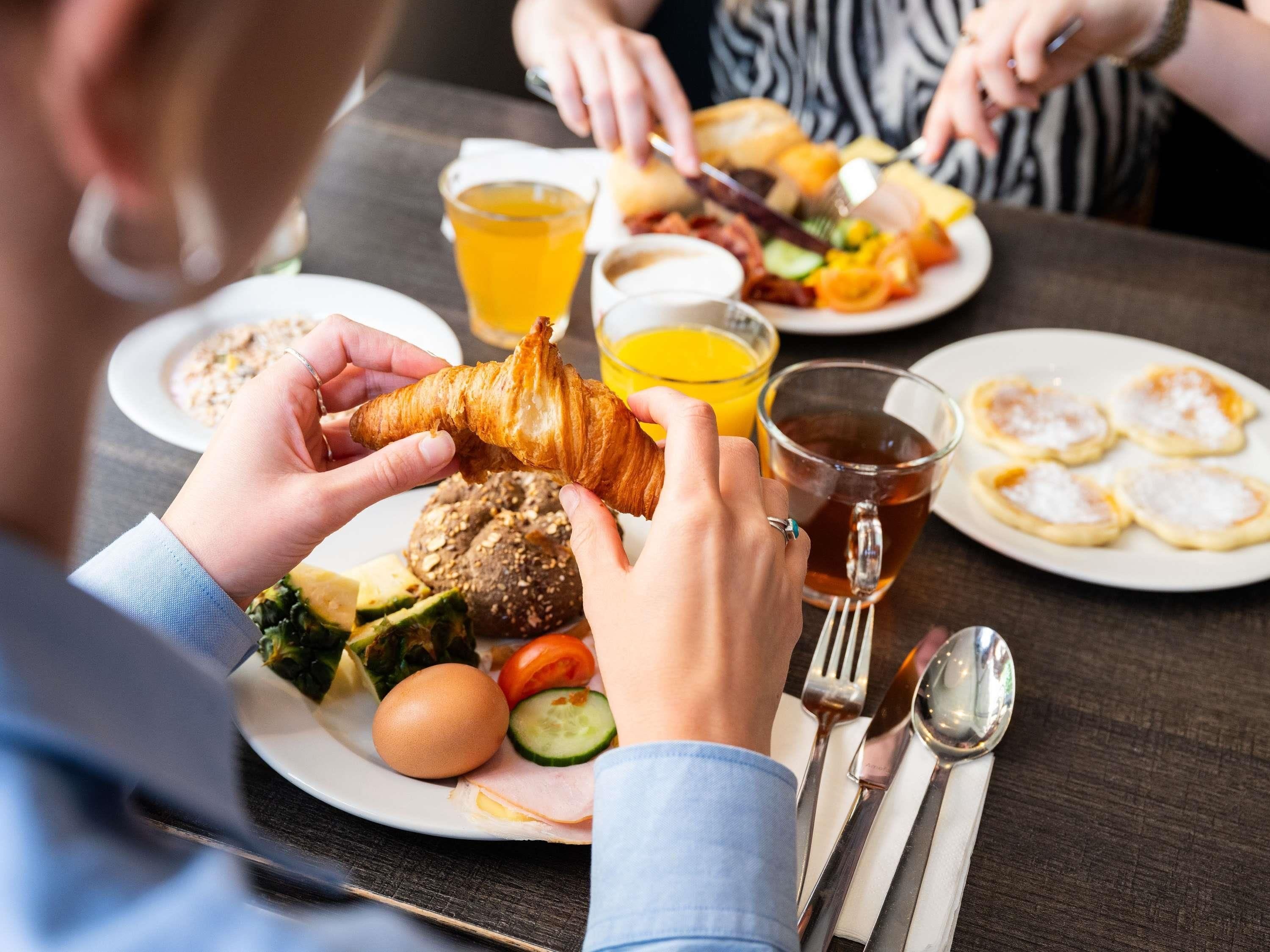Una mesa de comedor con platos de comida, cubiertos y un vaso de jugo de naranja.
