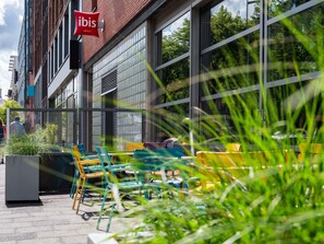 A hotel exterior with outdoor seating, large windows, and a visible 'ibis' sign. - ibis Amsterdam Centre Stopera (Amsterdam)