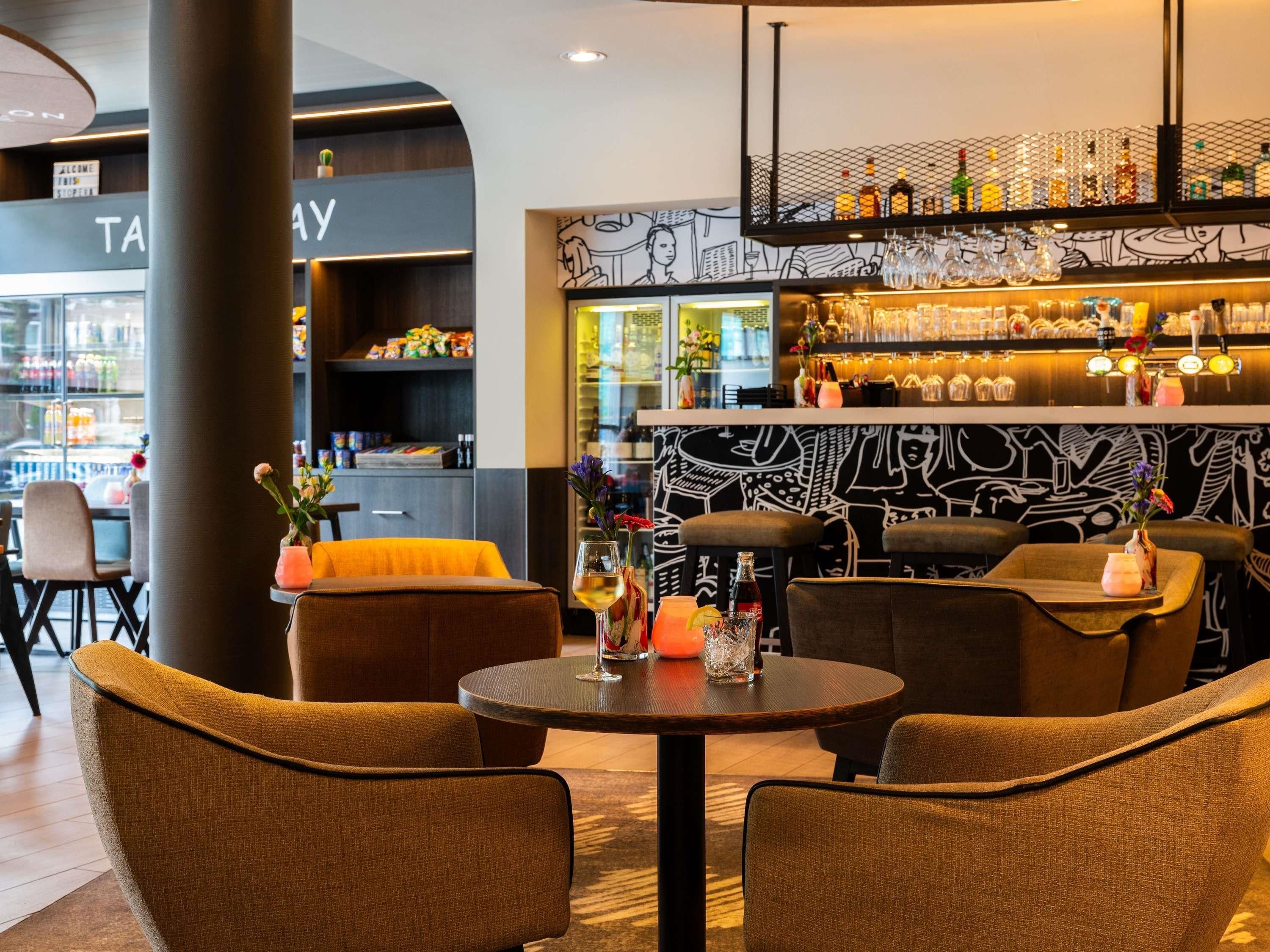 Eine Bar mit Sitzgelegenheiten, einer Theke mit Flaschen und einem 'TAXY'-Schild.