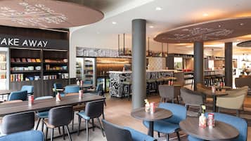 A modern restaurant with round tables, blue chairs, and a bar area.