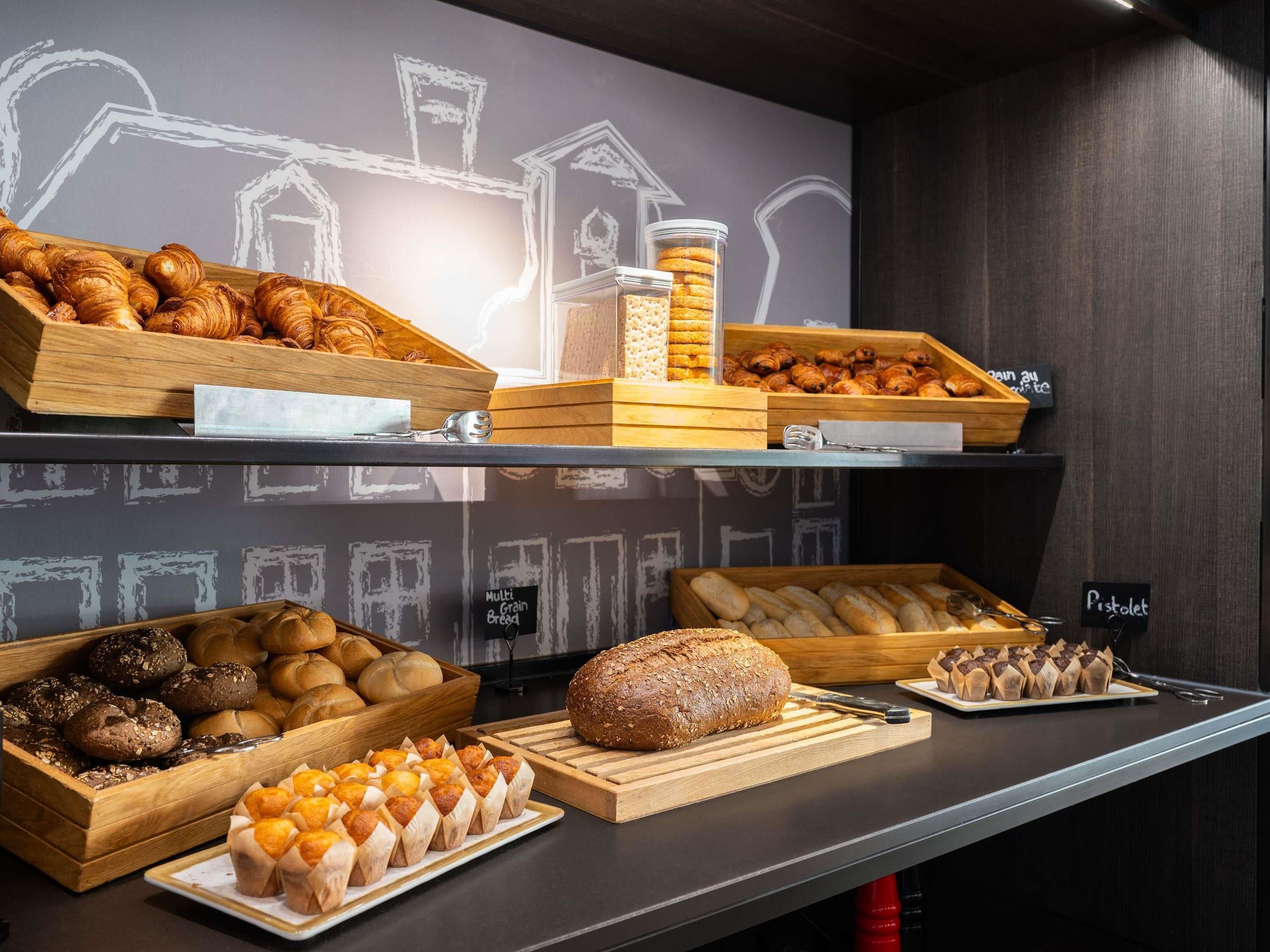 Une vitrine de boulangerie présentant une variété de produits de boulangerie, notamment des croissants, du pain aux céréales et des pâtisseries.