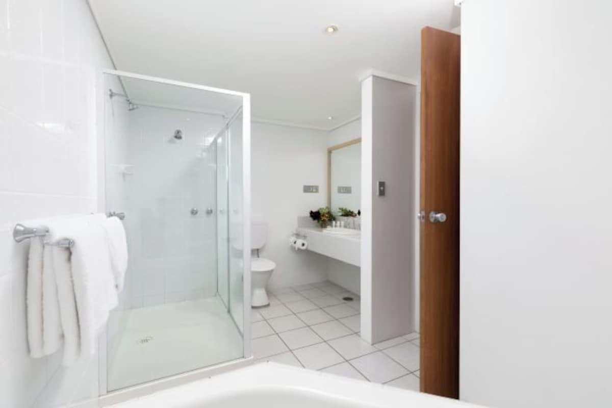 Un baño moderno con ducha envuelta en vidrio, inodoro blanco y puerta de madera.