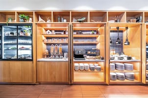 Una zona de cocina con estanterías de madera, una cafetera y distintos utensilios de cocina.