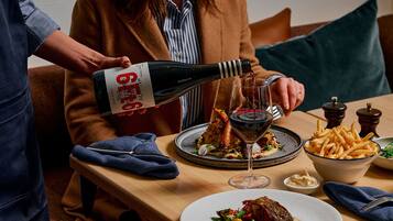 A dining table with a bottle of wine, a glass, and plates of food.