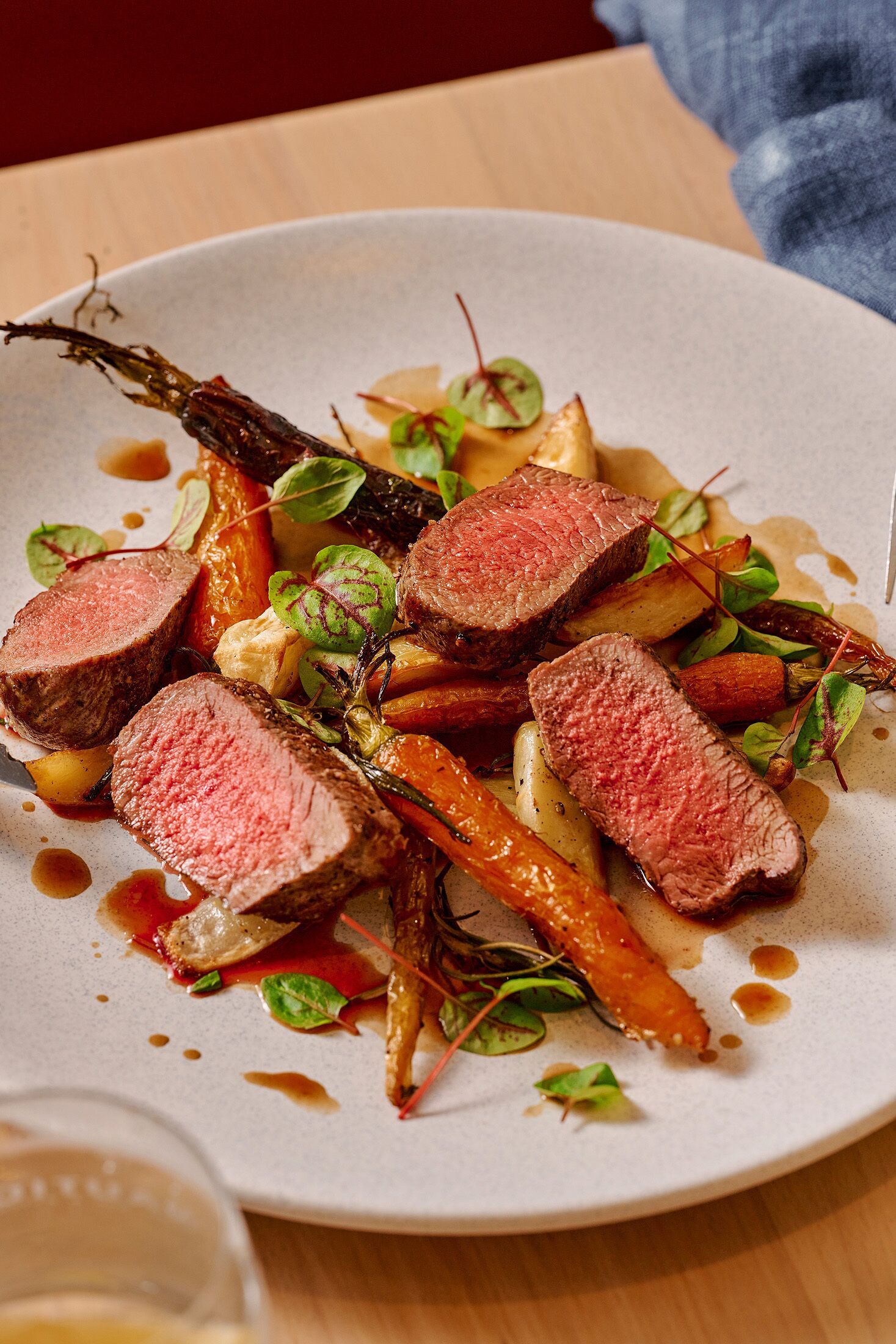 Une assiette de nourriture composée de viande en tranches, de légumes et de sauce.