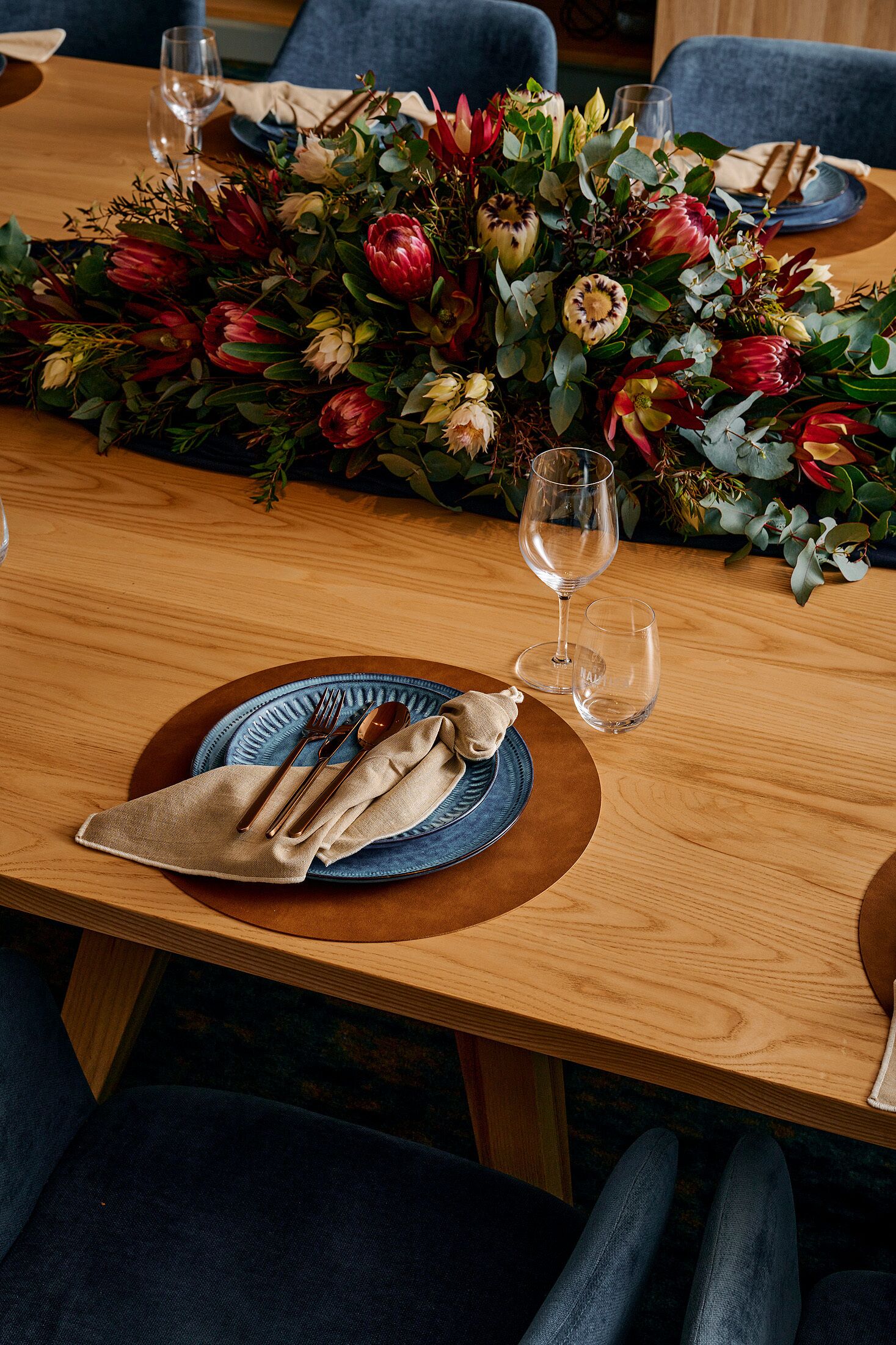 Una mesa de comedor dispuesta con platos, cubiertos y un florero.