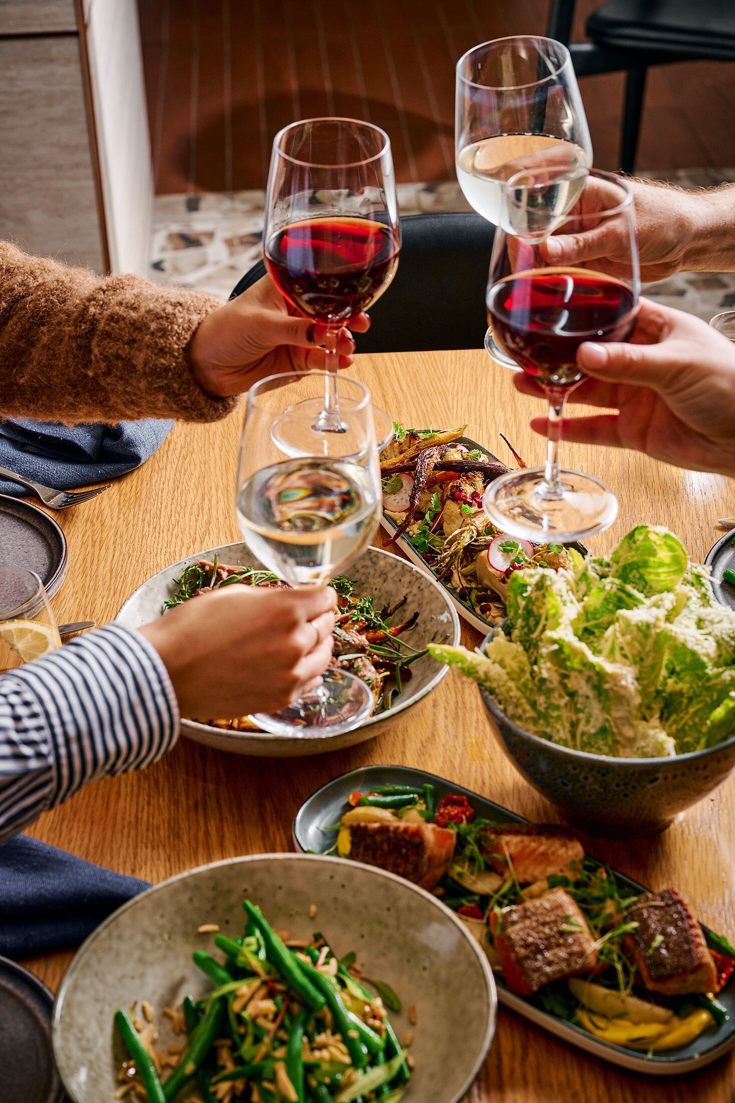 Una mesa de comedor con diversos platos y copas de vino tinto.