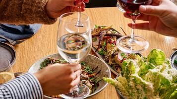 Una mesa de comedor con diversos platos y copas de vino tinto.