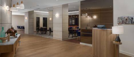 Un amplio y moderno vestíbulo de hotel con suelo de madera, una recepción y una zona de comedor.