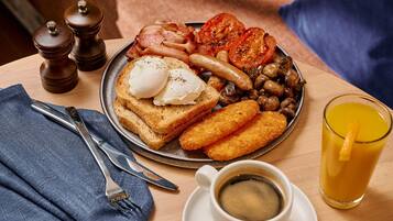 Une assiette de petit-déjeuner comprenant des toasts, des œufs, des saucisses, des champignons et des tomates.