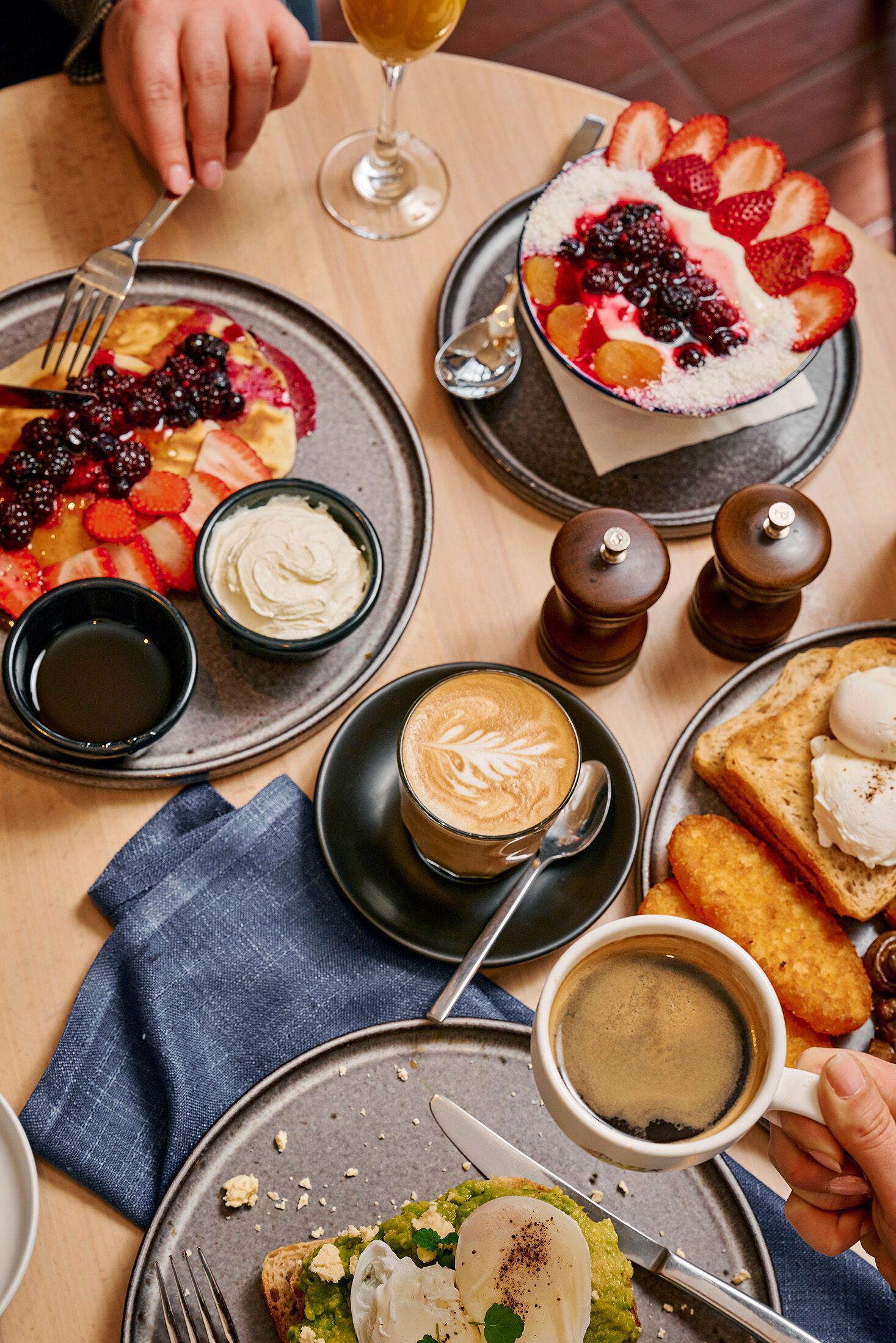 Ein Tisch mit verschiedenen Frühstücksangeboten, darunter Pfannkuchen, Toast, Kaffee und ein Dessert mit Beeren.