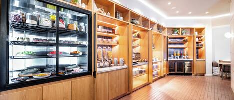 Een ruime, goed verlichte keuken met houten kasten en planken, gevuld met verschillende soorten levensmiddelen en keukengerei.