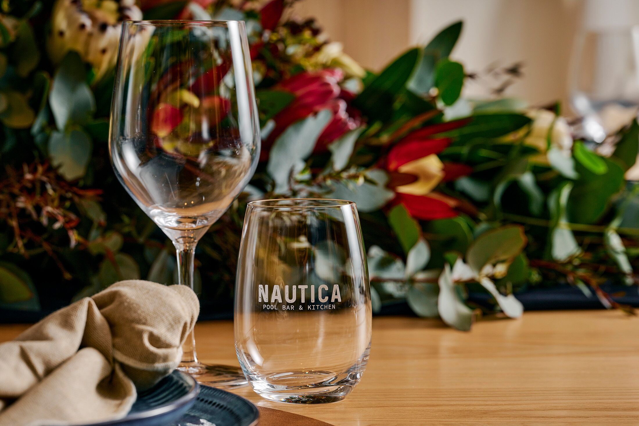 Duas taças de vidro transparentes com o texto "NAUTICA POOL BAR & KITCHEN" em uma delas.